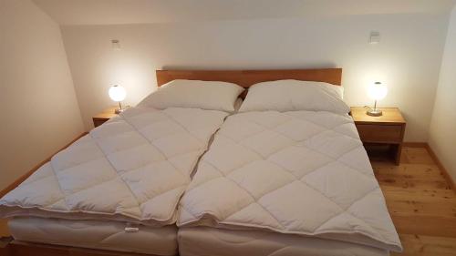 a large white bed with two lamps on two tables at Ferienhaus Murmeltier am Klippitztörl in Klippitztorl