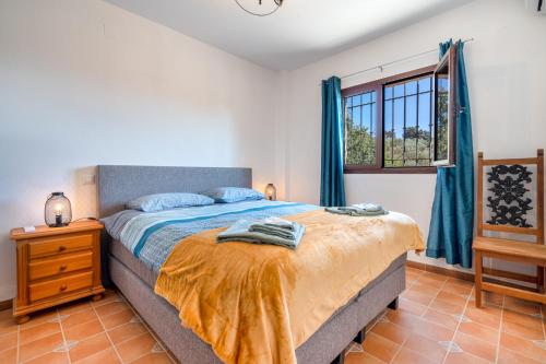 1 dormitorio con 1 cama con cortinas azules y ventana en Hacienda La buena vida B&B en appartementen casita la bruja, en Algarinejo