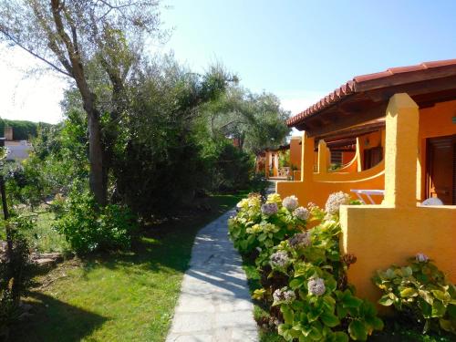 a house with a walkway next to a yard with flowers at Residence La Pineta in Budoni