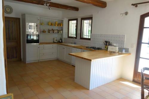 une cuisine avec des armoires blanches et un comptoir en bois dans l'établissement Villa Neville, à Châteaurenard