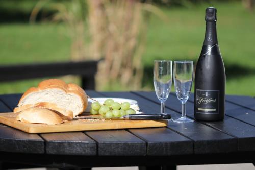 a table with a bottle of wine and a plate of bread and grapes at Spacious 3-Bedroom 3-bathroom country cottage in Haverfordwest