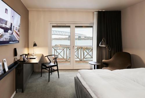 a hotel room with a bed and a desk and a window at Comwell Kongebrogaarden in Middelfart