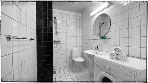 a white tiled bathroom with a toilet and a sink at Bergvegen Guesthouse Aalesund in Ålesund