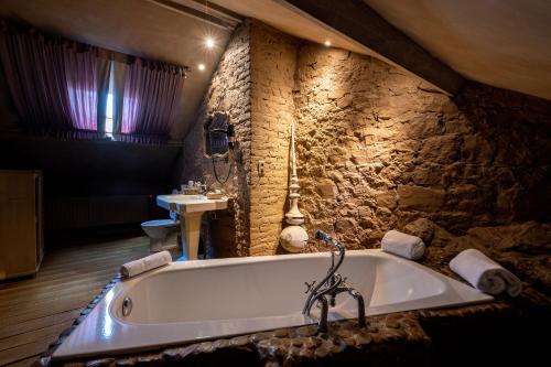 a bath tub in a bathroom with a stone wall at Les chambres du 7 by Juliette - Maison Caerdinael in Durbuy