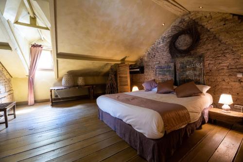 Les chambres du 7 by Juliette - Maison Caerdinael في دربي: غرفة نوم بسرير كبير وجدار حجري