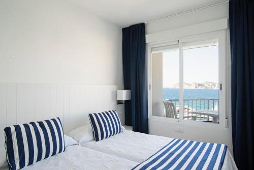a bedroom with a bed with a view of the ocean at Apartamentos La Mar in Benidorm