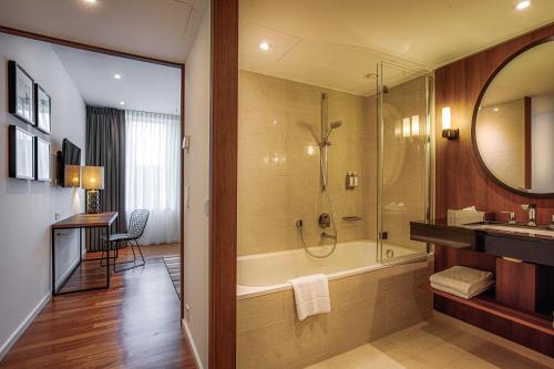 a bathroom with a tub and a sink and a mirror at AMERON Hamburg Hotel Speicherstadt in Hamburg