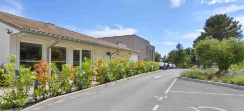 an empty parking lot with flowers next to a building at Kyriad Résidence Cabriès - Plan de Campagne in Cabriès