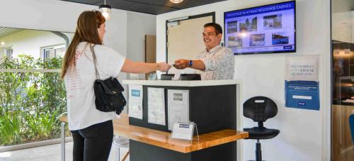 a man and a woman shaking hands at a counter at Kyriad Résidence Cabriès - Plan de Campagne in Cabriès