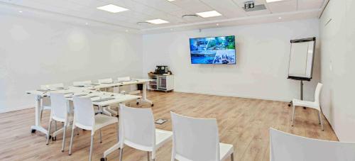 a room with tables and white chairs and a screen at Kyriad Résidence Cabriès - Plan de Campagne in Cabriès