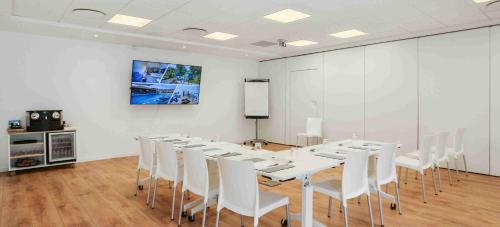a conference room with a long table and white chairs at Kyriad Résidence Cabriès - Plan de Campagne in Cabriès