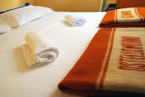 two rolled towels on a bed in a hotel room at Hi! Ostello Milano in Milan