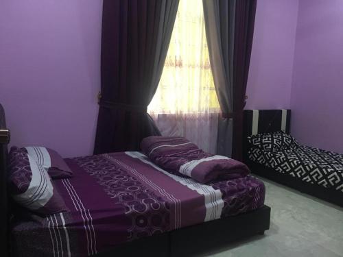 ein Schlafzimmer mit einem lila Bett und einem Fenster in der Unterkunft Cikgu CTZ Homestay (B) in Kampong Kubang Bemban