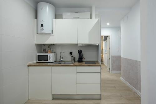a kitchen with white cabinets and a microwave at ROSE Apartamentos in Granada