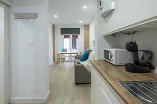a kitchen with a microwave and a living room at ROSE Apartamentos in Granada