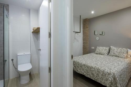 a small bedroom with a bed and a toilet at ROSE Apartamentos in Granada