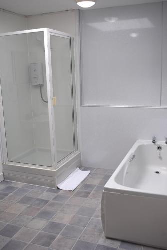 a bathroom with a shower and a white tub at Kelpies Serviced Apartments- Campbell in Pumpherston