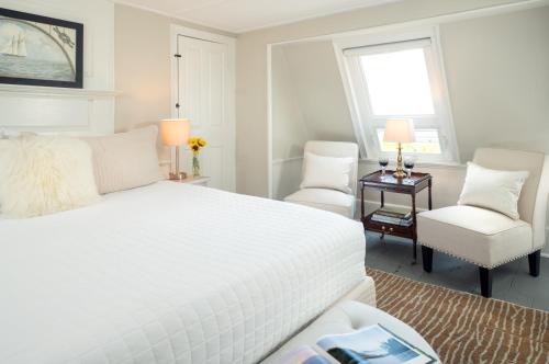 a white bedroom with a bed and two chairs at Waldo Emerson Inn in Kennebunkport