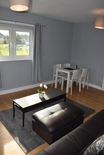 ein Wohnzimmer mit einem Sofa und einem Tisch in der Unterkunft Kelpies Serviced Apartments- Campbell in Pumpherston