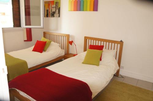 2 camas con almohadas coloridas en una habitación en Appartement T3 Climatisé entre mer et centre Nice, en Niza