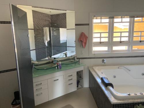 a bathroom with a tub and a large mirror at Casa de Campo Alto Padrao in Piracaia