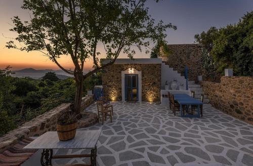 un patio con tavoli e sedie e un edificio di The Aegean blue country house Old Milos a Lagoúdi Zía