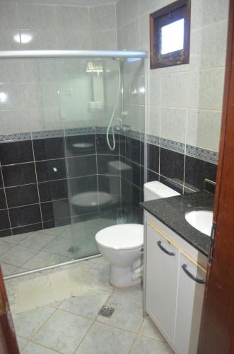 a bathroom with a shower and a toilet and a sink at Hotel Pousada Viking in Jacumã