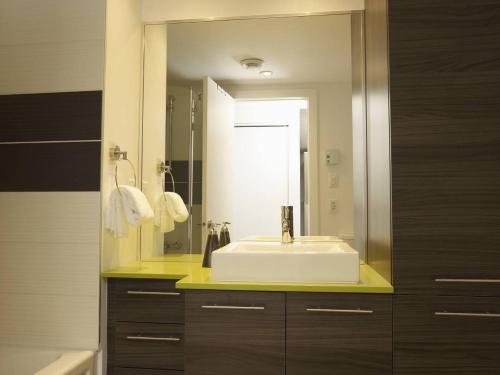 ein Badezimmer mit einem Waschbecken und einem großen Spiegel in der Unterkunft Les Immeubles Charlevoix - Le 1168 in Québec