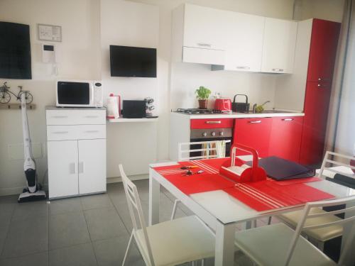 uma cozinha com uma mesa vermelha e armários brancos em Appartamento Bellavista em Martinsicuro