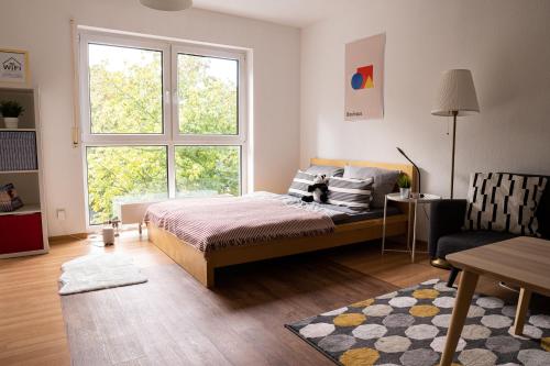een slaapkamer met een bed en een groot raam bij FULL HOUSE Studios - KornhausDeluxe Apartment - Balkon, WiFi in Dessau