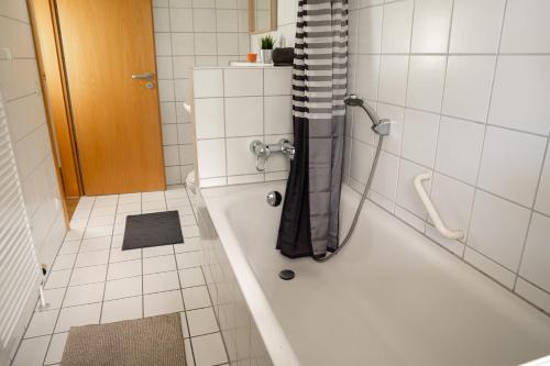 a bathroom with a bath tub with a shower curtain at FULL HOUSE Studios - KornhausDeluxe Apartment - Balkon, WiFi in Dessau