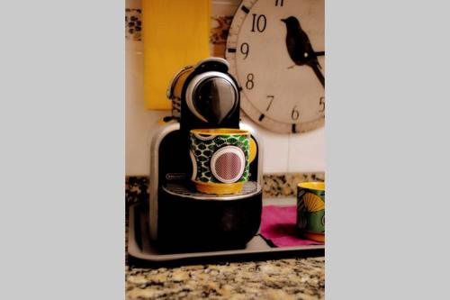 a kitchen counter with a coffee maker and a clock at Casa Luna, junto playa y Barcelona Centro in Badalona