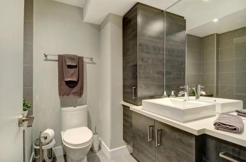 W łazience znajduje się umywalka, toaleta i lustro. w obiekcie Les Immeubles Charlevoix - Le 1175 w mieście Quebec City