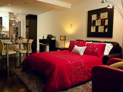 a red bed in a living room with a kitchen at Les Immeubles Charlevoix - Le 1176 in Quebec City