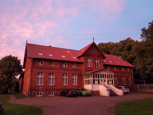 ein großes rotes Gebäude mit davor geparkt in der Unterkunft Gutshof Kämmerich in Altkalen