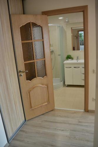 a bathroom with a wooden door and a sink at Dzintari in Liepāja