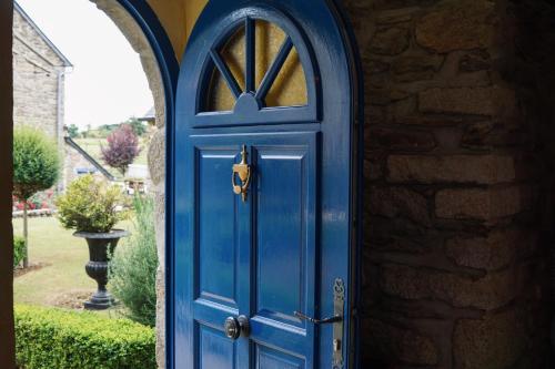 a blue door on a house with a stone wall at Manoir Des Douets Fleuris in Cancale