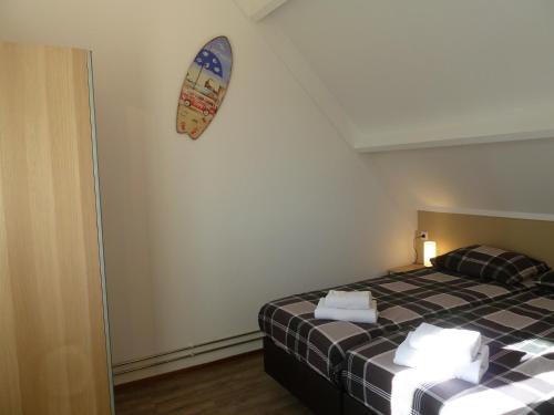 1 dormitorio con cama y tabla de surf en la pared en Vacation home Zwaantje #DKR2, en Callantsoog