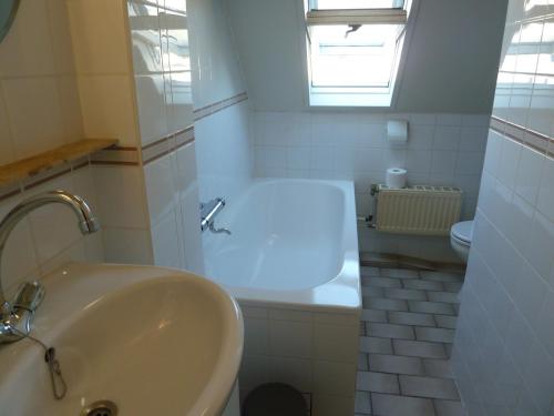 La salle de bains blanche est pourvue d'une baignoire et d'un lavabo. dans l'établissement Vacation home Zwaantje #DKR2, à Callantsoog