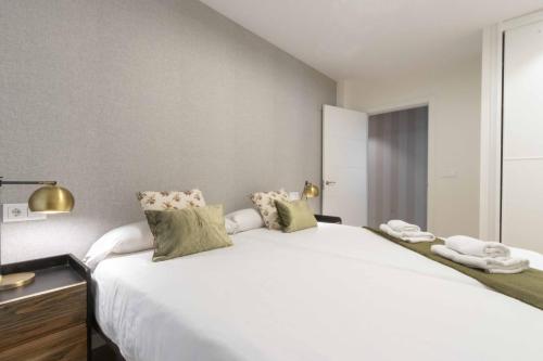 1 dormitorio con 1 cama grande con sábanas y almohadas blancas en The Rentals Collection - Palace II, en San Sebastián