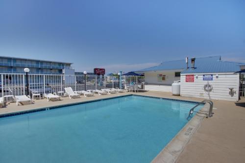 a large swimming pool with lounge chairs and a building at Thunderbird Beach Motel in Ocean City