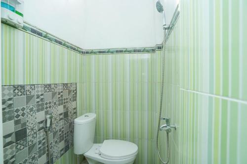 a bathroom with a white toilet and a shower at SPOT ON 2479 Berkah Residence Syariah in Gresik