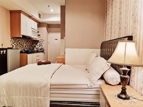 Apartemen grand kamala lagoon by 21 Room في بيكاسي: غرفة نوم بسرير وطاولة مع مصباح