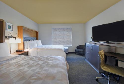 a hotel room with two beds and a flat screen tv at Holiday Inn Grand Rapids North - Walker by IHG in Walker