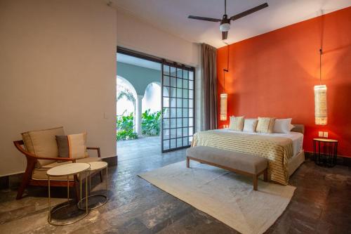 a bedroom with a large bed and a chair at Antelar Casa Destino in Mérida
