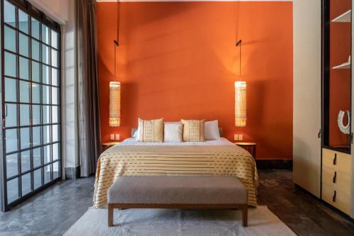 a bedroom with a large bed with an orange wall at Antelar Casa Destino in Mérida
