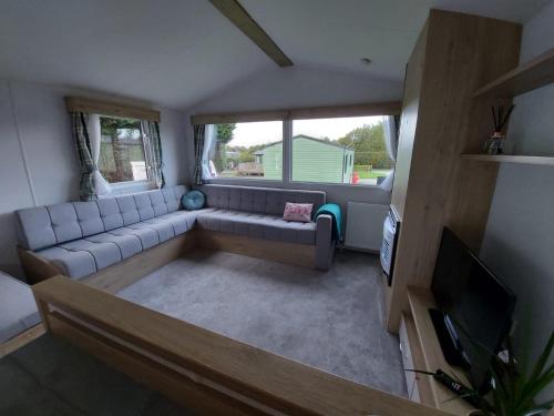 ein Wohnzimmer mit einem Sofa und einem TV in der Unterkunft Woofles Luxury Caravan at Knaresborough Lido in Knaresborough