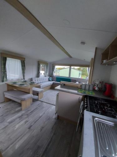 a kitchen and living room with a couch and a stove at Woofles Luxury Caravan at Knaresborough Lido in Knaresborough