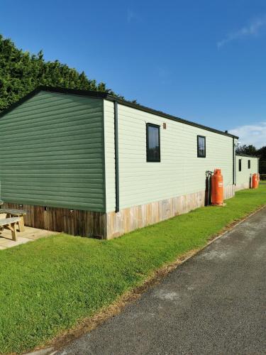 a large white building with a green garage at Woofles Luxury Caravan at Knaresborough Lido in Knaresborough
