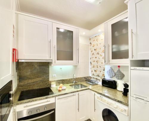 a kitchen with white cabinets and a sink at Tália XI - Near the beach - Vilamoura in Vilamoura